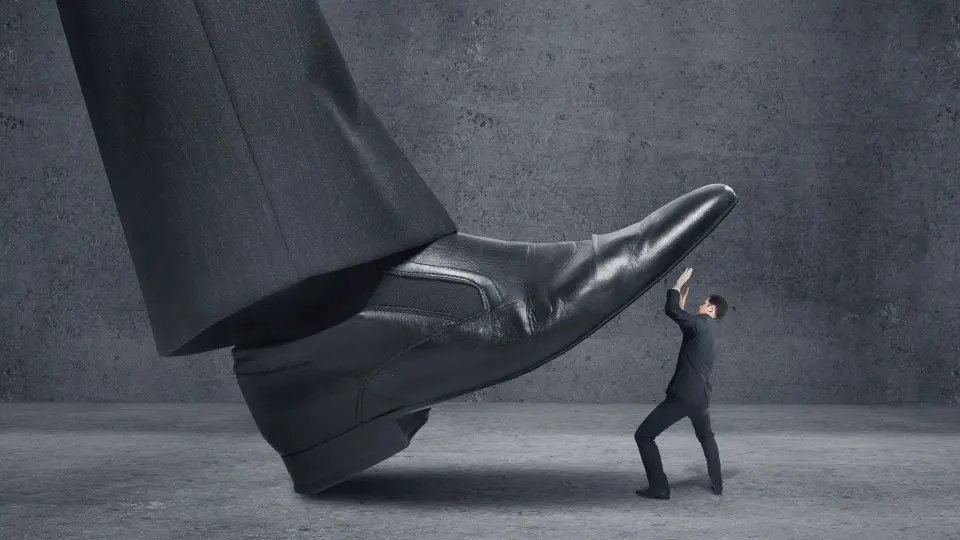 A tiny man being crushed by a giant shoe.