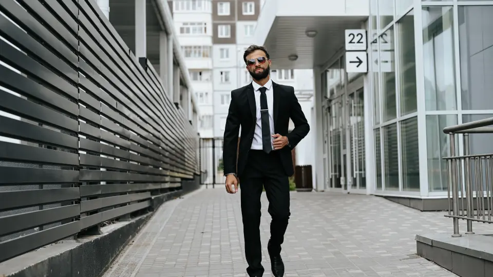 un uomo che porta un completo camina per la strada fanno bella figura. a man in a suit walks along the street looking sharp.